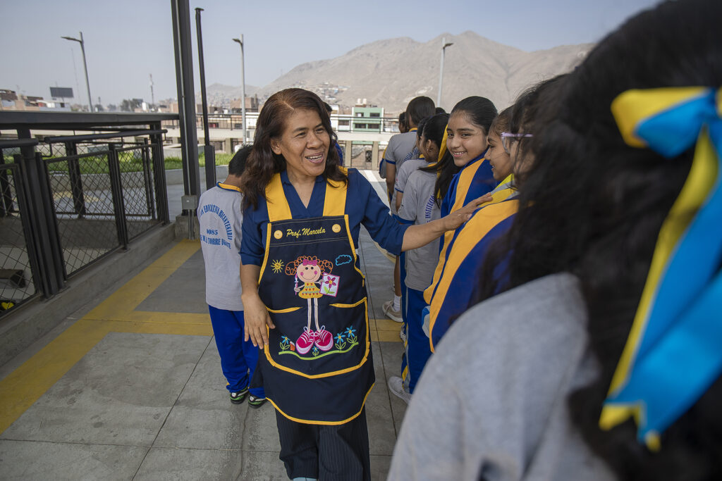 A woman stands outside next to a line of students