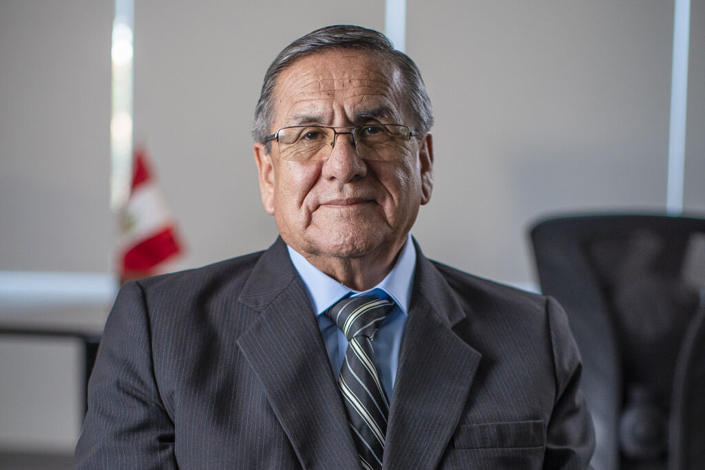 A man sits in an office holding pieces of paper